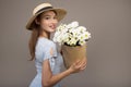 Beautiful girl in a blue dress with white flowers in her hands on a gray background. Young happy woman holding a basket with Royalty Free Stock Photo