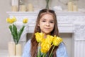 Beautiful girl in a blue dress with yellow tulip flowers in her hands on a light background Royalty Free Stock Photo