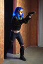 Beautiful girl with blue hair holding gun in strikeball location background