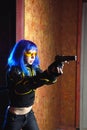 Beautiful girl with blue hair holding gun in strikeball location background Royalty Free Stock Photo