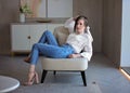 Beautiful girl in blue jeans and white shirt on a chair. Portrait of a young lady