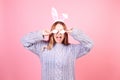 Beautiful girl in a blue sweater on a pink background. Woman with bunny ears, posing for easter, covering her eyes with easter Royalty Free Stock Photo