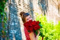 Beautiful and girl with a bouquet of red roses stands on the background of an old brick wall. Royalty Free Stock Photo