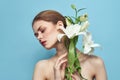 Beautiful girl with a bouquet of white flowers on a blue background cropped view naked shoulders portrait