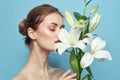 Beautiful girl with a bouquet of white flowers on a blue background cropped view naked shoulders portrait