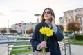 Beautiful girl with bouquet of yellow spring flowers, young woman talking on phone Royalty Free Stock Photo