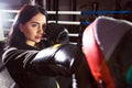 A beautiful girl in boxing gloves hits her paws in the ring. Sexy woman is training in the gym. Beautiful brunette is engaged in Royalty Free Stock Photo