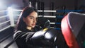 A beautiful girl in boxing gloves hits her paws in the ring. Sexy woman is training in the gym. Beautiful brunette is engaged in Royalty Free Stock Photo