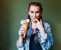 Beautiful girl with braids sitting in a cafe and eating huge multi-colored ice cream in a waffle cone. Licking finger Royalty Free Stock Photo