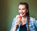 Beautiful girl with braids sitting in a cafe and eating huge multi-colored ice cream in a waffle cone. Smiling at the camera