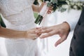 Beautiful girl bride in wedding white dress puts on the groom`s finger the wedding gold ring Royalty Free Stock Photo