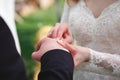 Beautiful girl bride in wedding white dress puts on the groom`s finger the wedding gold ring Royalty Free Stock Photo