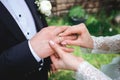Beautiful girl bride in wedding white dress puts on the groom`s finger the wedding gold ring Royalty Free Stock Photo