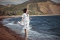 Beautiful girl, bride, in white dress, barefoot, runs on the beach, on the water and laughs. Royalty Free Stock Photo