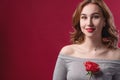 Beautiful girl with bright makeup, holding a rose in her hands on a red background in the studio. The concept of youth Royalty Free Stock Photo