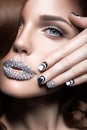 Beautiful girl with bright nails and lips of crystals, long eyelashes and curls. Beauty face. Royalty Free Stock Photo