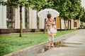 A beautiful girl in a bright rain jacket walks under an umbrella during the rain on the street Royalty Free Stock Photo