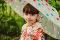 A beautiful girl in a bright raincoat walks during the rain under an umbrella. Soft focus Royalty Free Stock Photo