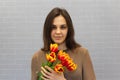 Beautiful girl in the brown dress with flowers tulips in hands on a light background Royalty Free Stock Photo