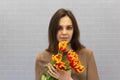 Beautiful girl in the brown dress with flowers tulips in hands on a light background Royalty Free Stock Photo