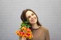 Beautiful girl in the brown dress with flowers tulips in hands on a light background Royalty Free Stock Photo