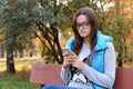 Beautiful girl in glasses sits on a bench and writes and reads S Royalty Free Stock Photo