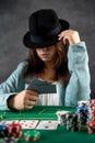 beautiful girl came to the night casino to play poker at a wide green table. a woman in a hat