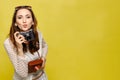 A beautiful girl in casual clothes with a vintage camera looks at the camera and sends a kiss