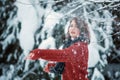 A beautiful girl of Caucasian appearance in a burgundy sweater throws snow. Winter day, snowy park. Outdoor games Royalty Free Stock Photo