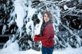 A beautiful girl of Caucasian appearance in a burgundy sweater throws snow. Winter day, snowy park. Outdoor games Royalty Free Stock Photo
