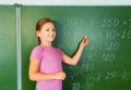 Beautiful girl with chalk in hand writes equation Royalty Free Stock Photo