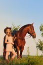 Beautiful girl with chestnut horse in evening field