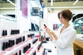 Beautiful girl chooses a lipstik in the store and thinks about her choice