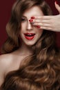 Beautiful girl with a classic make up, curls hair and red nails. Manicure design. Beauty face. Royalty Free Stock Photo