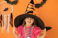 A beautiful girl with clear eyes puts on a big witch hat to celebrate Halloween. Royalty Free Stock Photo