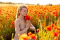 A beautiful girl with closed eyes meditates on a poppy field holding a bouquet of flowers Royalty Free Stock Photo