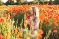 A beautiful girl with closed eyes meditates on a poppy field holding a bouquet of flowers Royalty Free Stock Photo