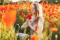 A beautiful girl with closed eyes meditates on a poppy field holding a bouquet of flowers Royalty Free Stock Photo