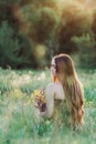 Beautiful girl collect flowers on field, young woman with long hair in dress walking on nature,summer tender photo in village