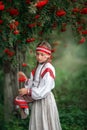 A beautiful girl collects bunches of mountain ash in the hem of her dress