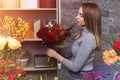 A beautiful girl collects a dark bouquet of burgundy red roses in her studio. Male florist creating beautiful bouquet in flower