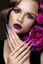 Beautiful girl with colorful make-up, flowers, retro hairstyle and long nails. Manicure design. The beauty of the face. Royalty Free Stock Photo