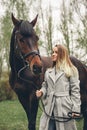 Beautiful girl communicates with a horse in the park