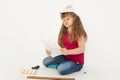 A beautiful girl in a construction cap, a hard hat with a screwdriver, a drill in her hands repairs a wooden stick