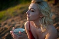 A beautiful girl, covered with a plaid in the evening at sunset, holds a mug of tea with two hands against the sea Royalty Free Stock Photo