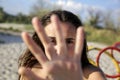 Beautiful girl covers her face with her hand on the sea coast