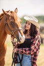 Beautiful girl in a cowgirl wear smiles at her brown horse Royalty Free Stock Photo