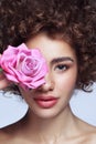 Beautiful girl with curly hair, clean makeup and pink rose in her hand Royalty Free Stock Photo