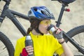 Beautiful girl cyclist pours tea from a thermos on the background of a Bicycle in the sand