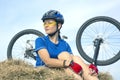 Beautiful girl cyclist sitting on dry grass on the background of the bike. Nature and man Royalty Free Stock Photo